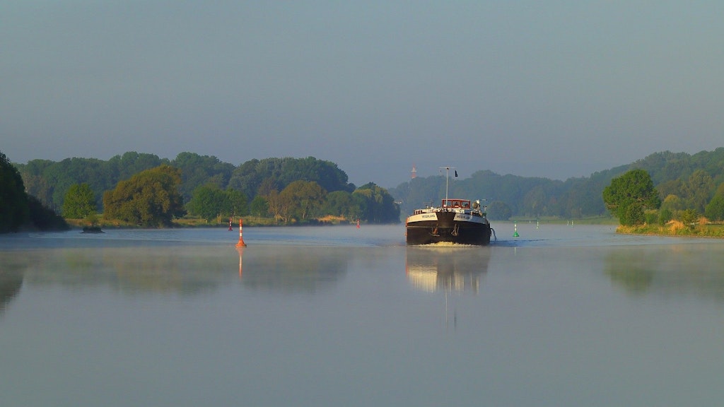 Blauer Rhein, blauer Himmel, grüner Wald; ein Binnenschiff auf dem Rhein