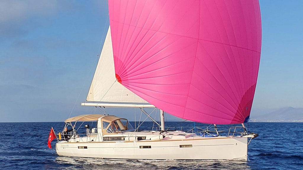 Uno yacht battente bandiera svizzera naviga con vela rosa.