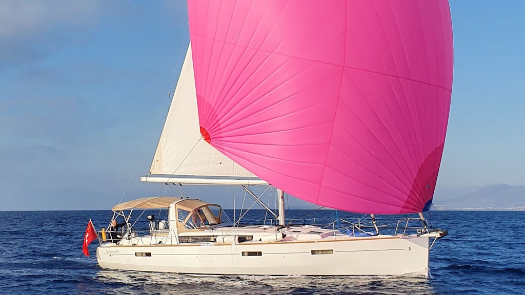 A yacht under the Swiss flag sails with a pink sail.