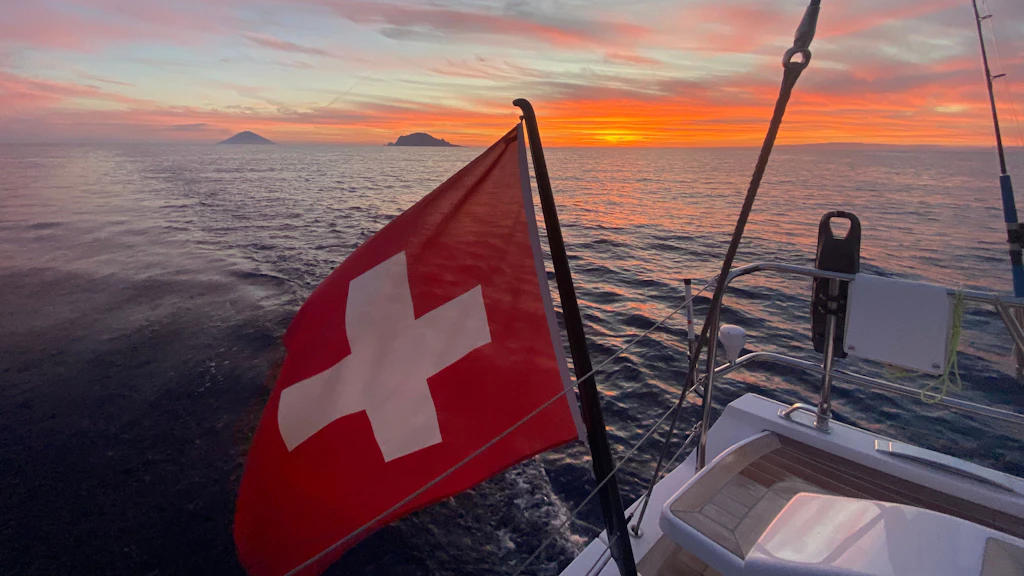 Die Schweizer Flagge auf dem Meer vor dem Vulkan von Stromboli.