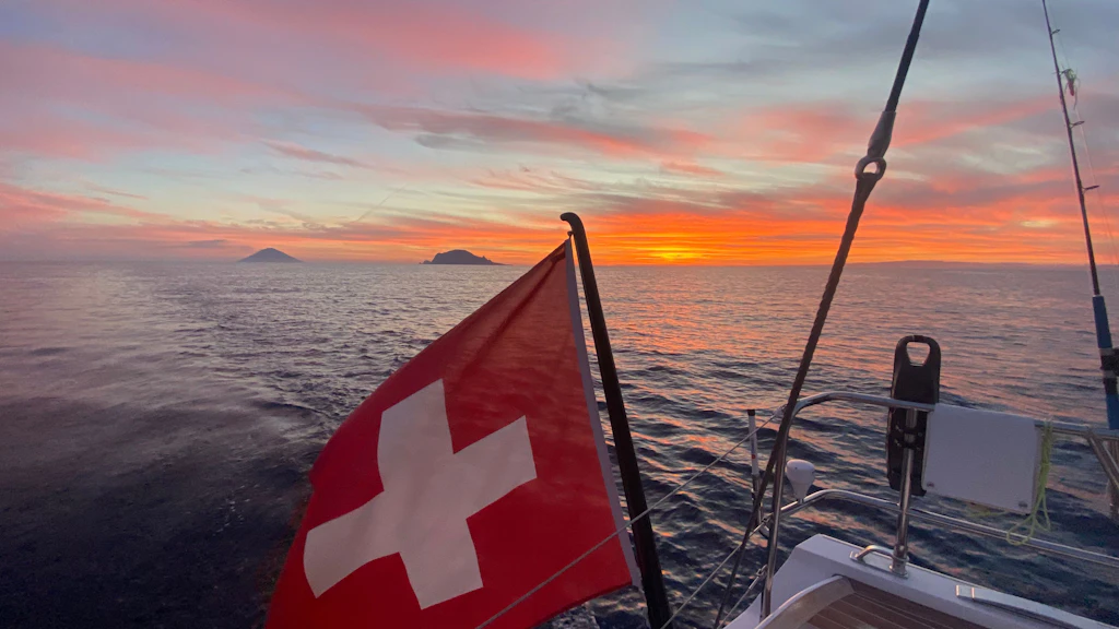 La bandiera svizzera sul mare davanti al vulcano di Stromboli. 